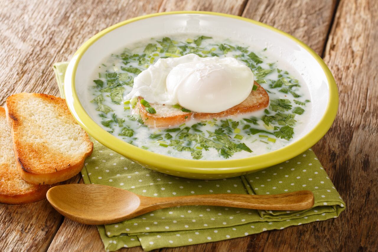 sopa de changua colombiana hecha con huevos, leche, hierbas y pan de cerca en un plato sobre la mesa.