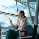 Joven con sus maletas de viaje esperando el vuelo en la terminal del aeropuerto.