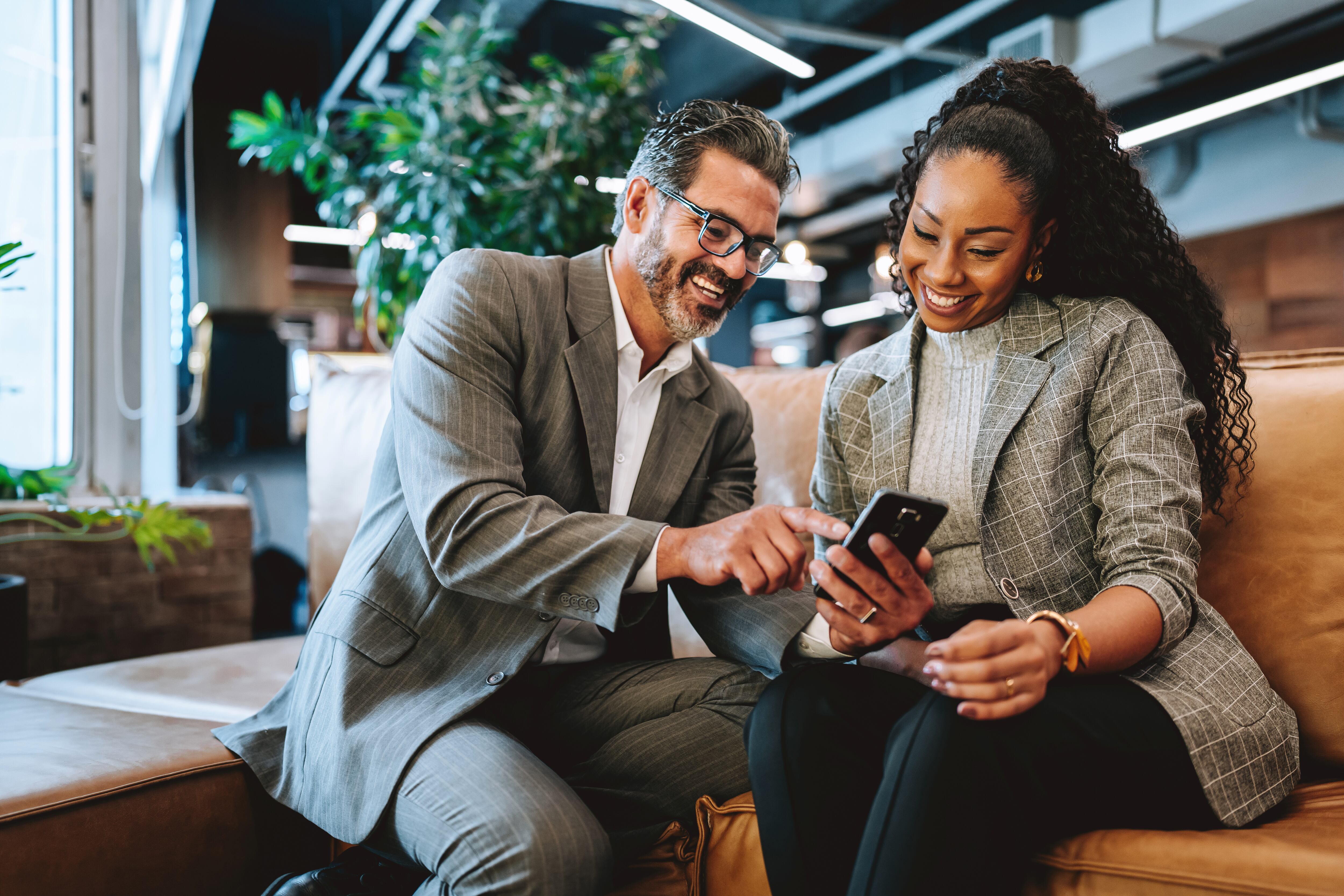 Two business people showing smartphone to coworker