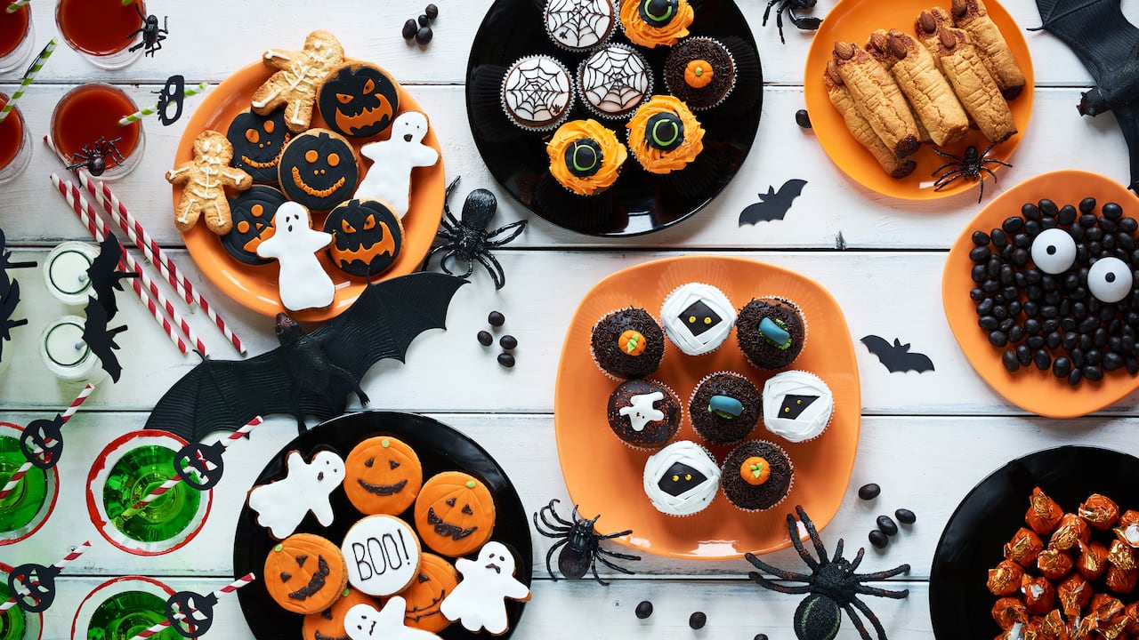 High angle view of Halloween cookies, candies, cupcakes, drinks on decorated table