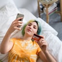 Mujer joven con cabello teñido está comprando en línea con una tarjeta de crédito. Foto: Getty Images