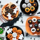 Vista de ángulo alto de galletas de Halloween, dulces, cupcakes, bebidas en mesa decorada