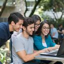 Retrato de un feliz grupo de estudiantes de la universidad usando una computadora portátil mientras estudian al aire libre - conceptos educativos