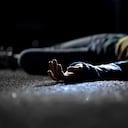 Bloody female victim of deadly car accident lying on road, close-up view at body