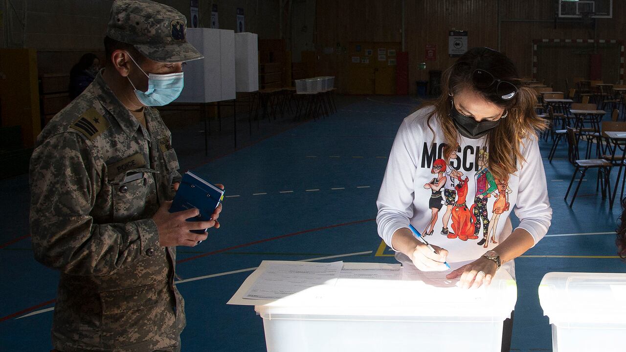 Una mujer instala mesas de votación en la escuela secundaria Portugal en Punta Arenas, Chile, el 20 de noviembre de 2021, en vísperas de las elecciones generales de Chile. - Siete candidatos participarán en las elecciones presidenciales de Chile, y las encuestas muestran dos claros favoritos en campos políticos opuestos: Gabriel Boric, de 35 años, de la alianza de izquierda Approve Dignity, que incluye al Partido Comunista, y el candidato de extrema derecha José Antonio Kast, de 55 años, del Partido Republicano. Partido: cada uno con aproximadamente una cuarta parte de la intención de voto declarada. (Foto de CLAUDIO REYES / AFP)