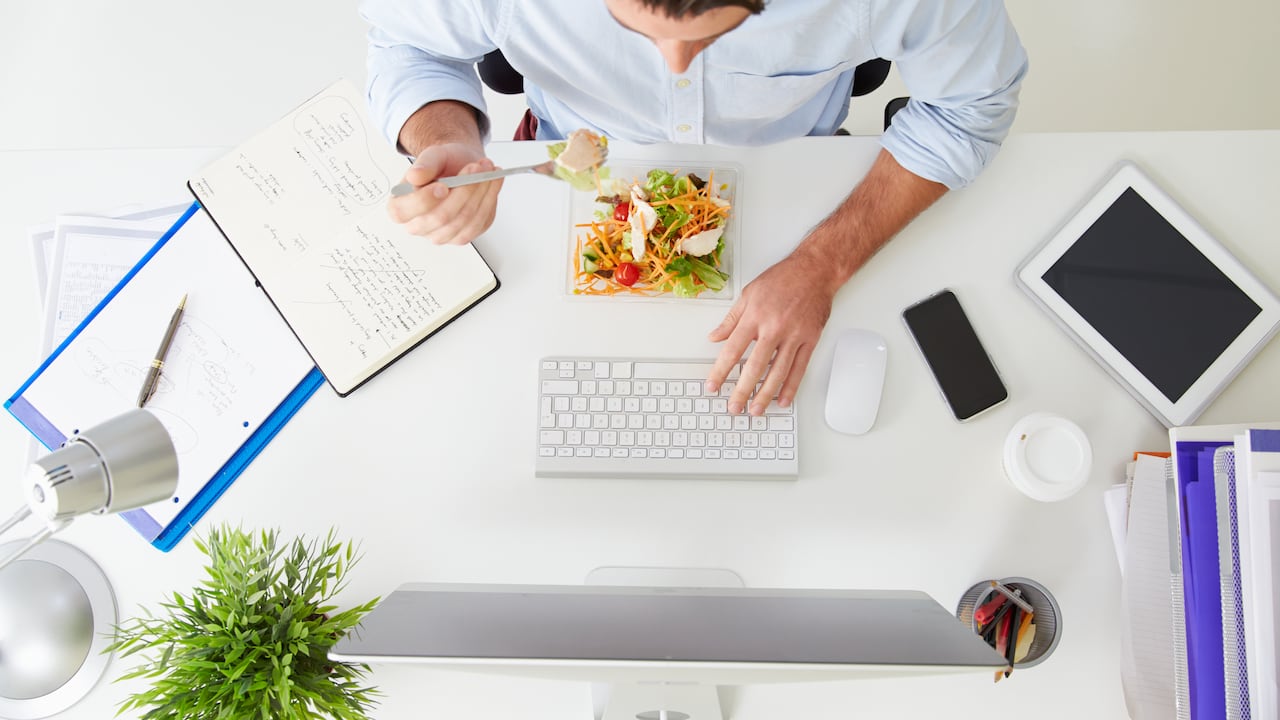 Vista aérea del empresario trabajando en equipo en la oficina comiendo el almuerzo