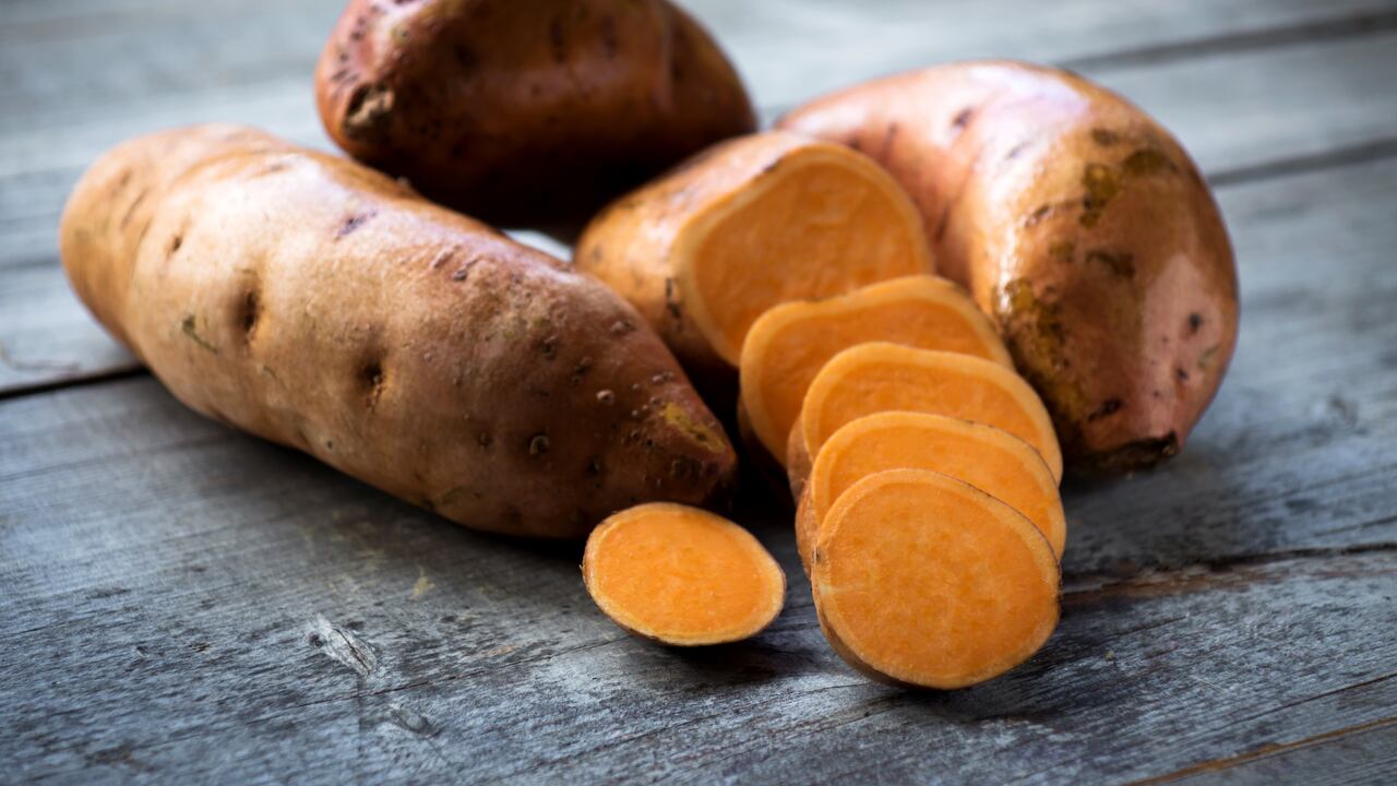 Raw sweet potatoes on wooden background closeup