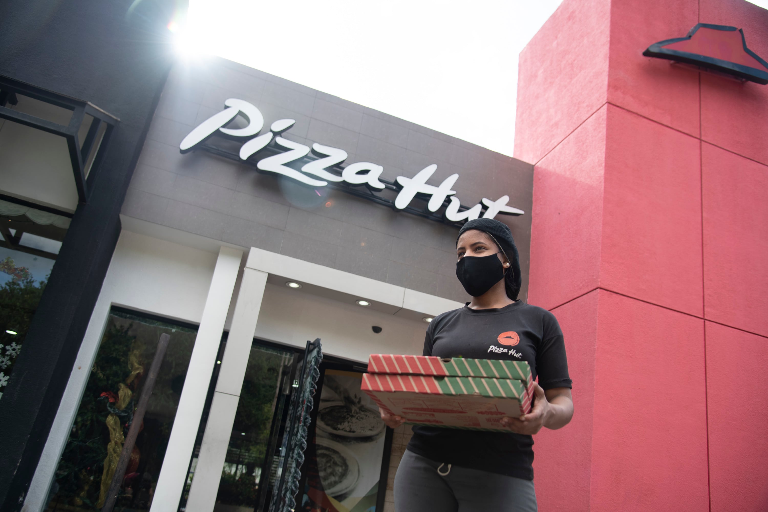 Pizza Hut employee carries pizza boxes