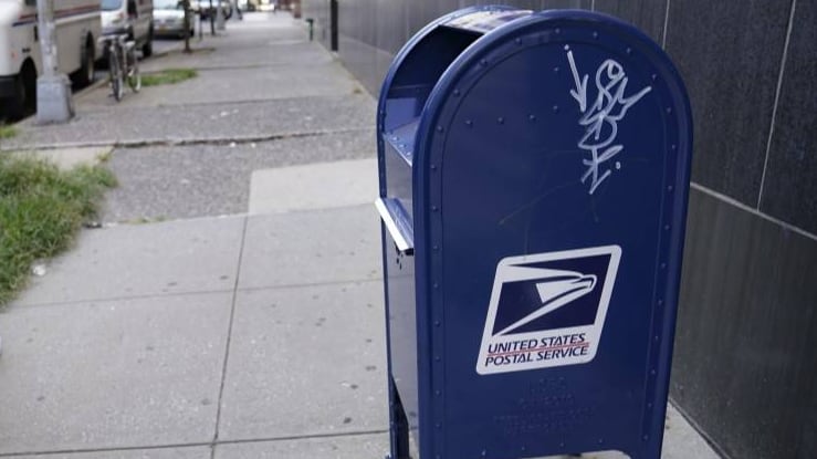 Una mujer pasa junto a un buzón del servicio postal en Nueva York.