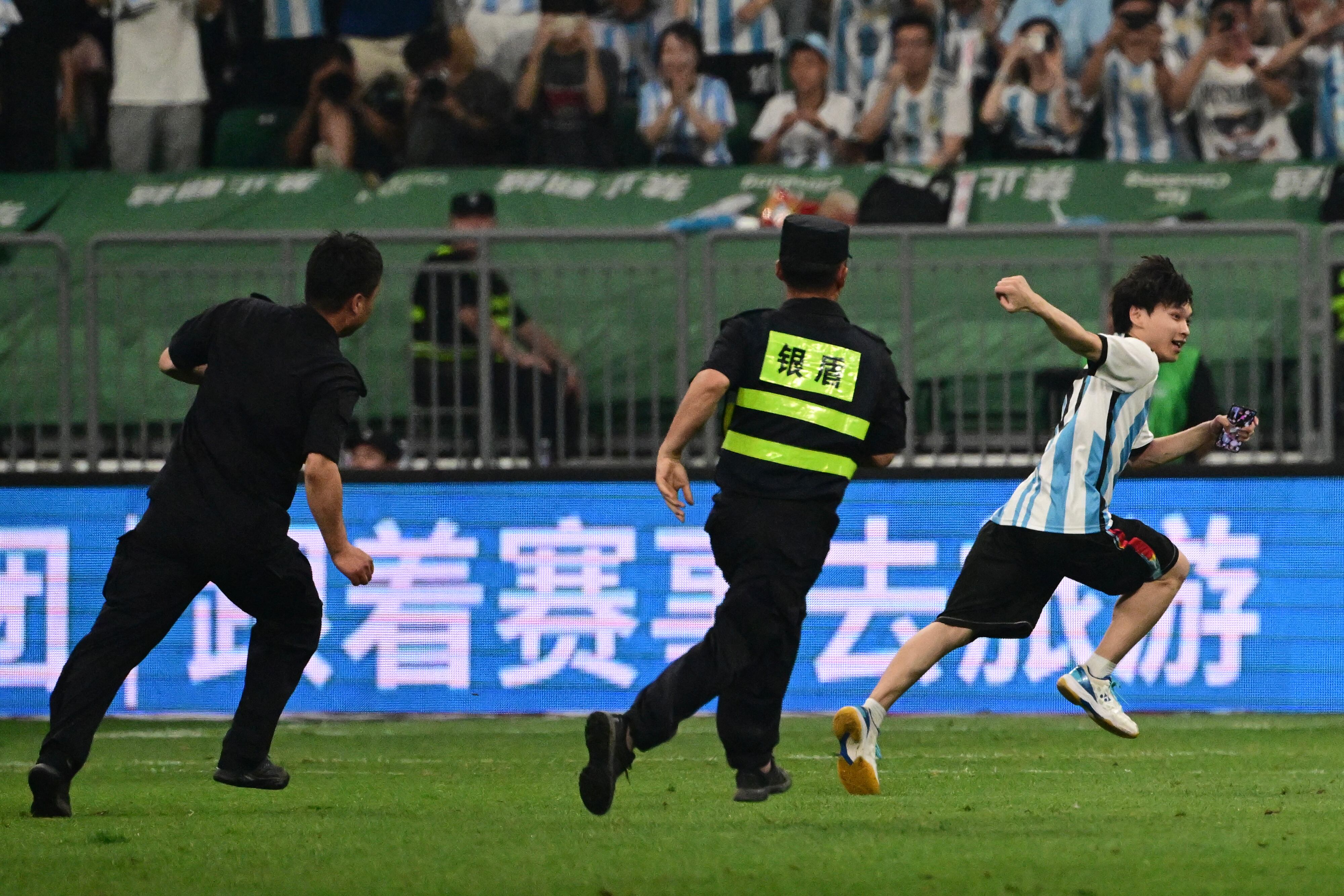 Un hincha chino saltó al campo para saludar a Messi en medio del partido. Foto: AFP.