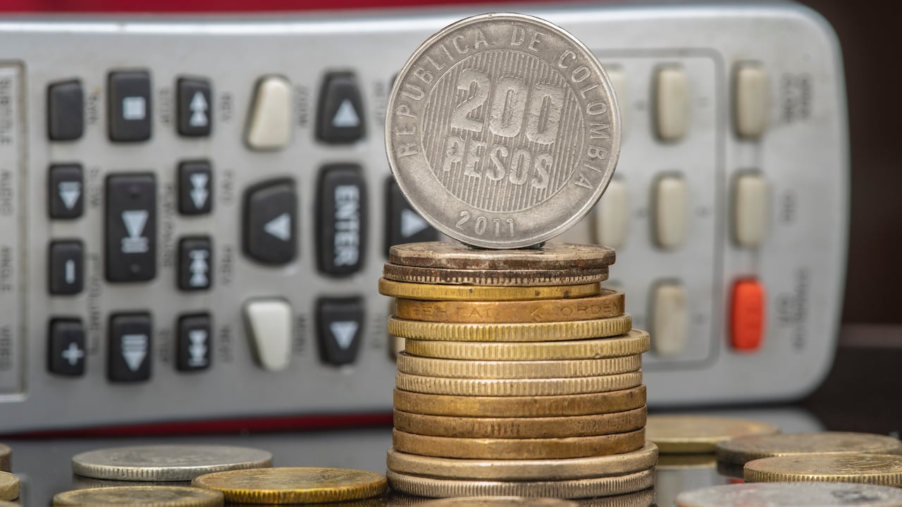 Pile and coins of Two Hundred Colombian Pesos with a calculator as a background. Income, expenses, taxes, financial data