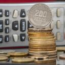 Pile and coins of Two Hundred Colombian Pesos with a calculator as a background. Income, expenses, taxes, financial data