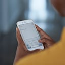 Persona enviando un mensaje desde su celular.