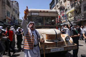 A protester gestures in front of an old bus which Palestinians used for land travel to Arab capitals before 1948, during a rally marking 'Nakba' day in the Ramallah city center in the occupied West Bank, on May 15, 2023. May 15 marks the "Nakba", or catastrophe, when hundreds of thousands of Palestinians were displaced from their homes following the creation of Israel 75 years ago. (Photo by HAZEM BADER / AFP)