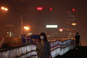 Una mujer se protege con una máscara por la nube de contaminación en Pekín (China).