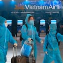 Personas con equipo de protección completo caminan por el aeropuerto Noi Bai en Hanoi, Vietnam, el viernes 12 de febrero de 2020. Un nuevo brote de COVID-19 en Vietnam ha ralentizado los negocios y los viajes durante el popular festival del año nuevo lunar. (Foto AP / Hau Dinh)
