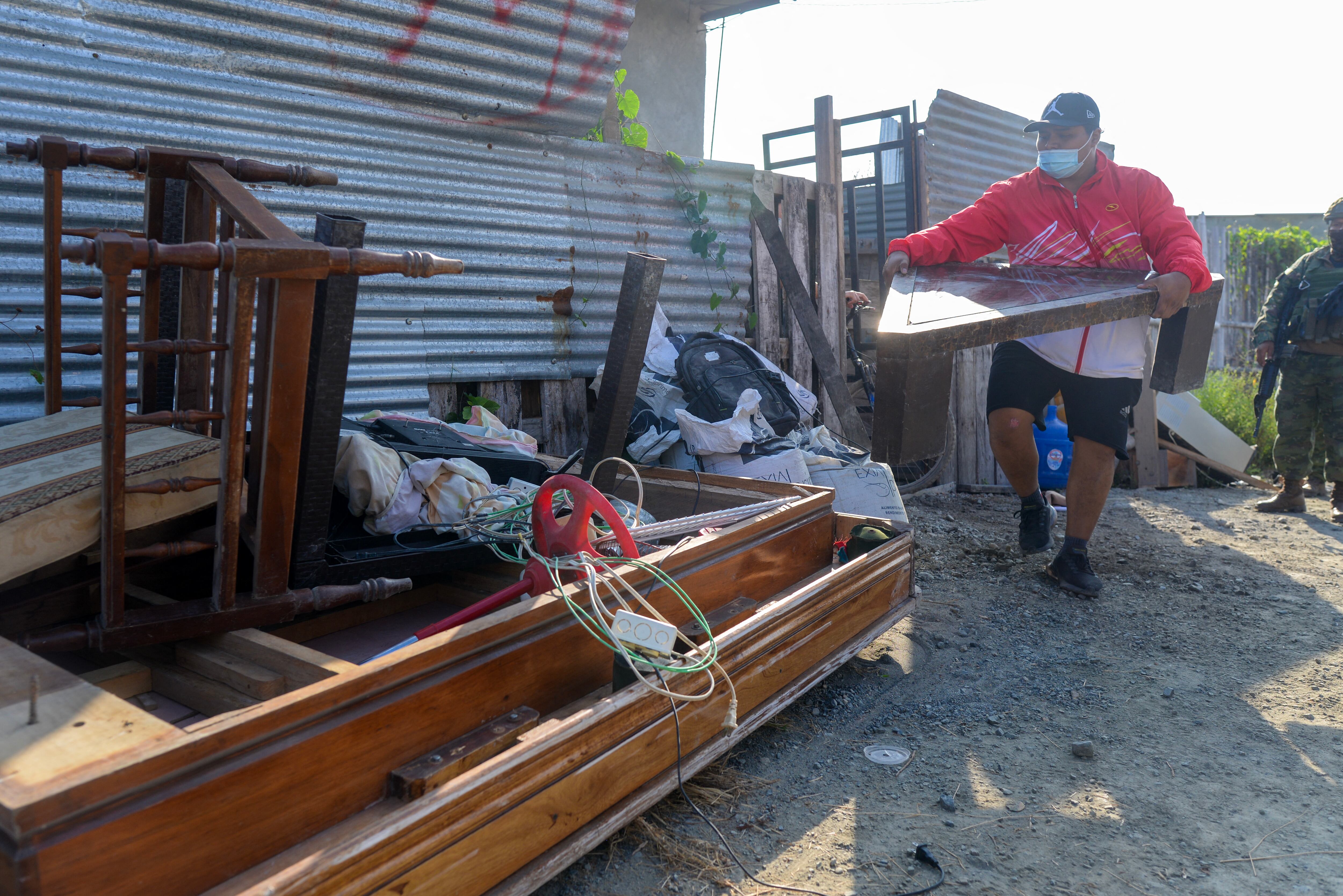 A man removes furniture and belongings from the people who had extorted and evicted his family after recovering their house during an operation carried out by the military and police in Duran, 10 km east of Guayaquil, Ecuador, on July 23, 2024. The mood is tense in the violent coastal town of Dur�n, which is guarded by soldiers and police. The small city, located on the banks of the Guayas River, is prized by drug traffickers for its estuaries, which have been converted into river routes to ports from which drugs are shipped. (Photo by Gerardo MENOSCAL / AFP)
