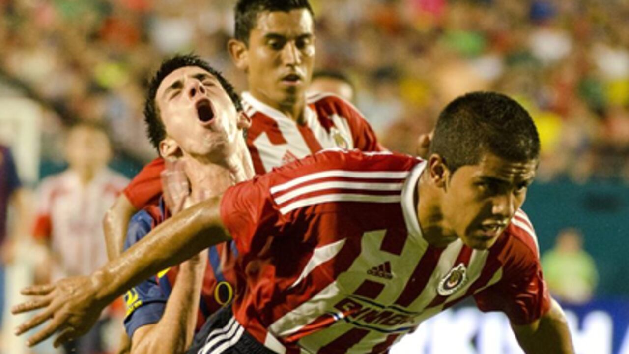 El jugador Xavier Baez (adelante) del Chivas Guadalajara choca contra Cuenca (c) del Barcelona.