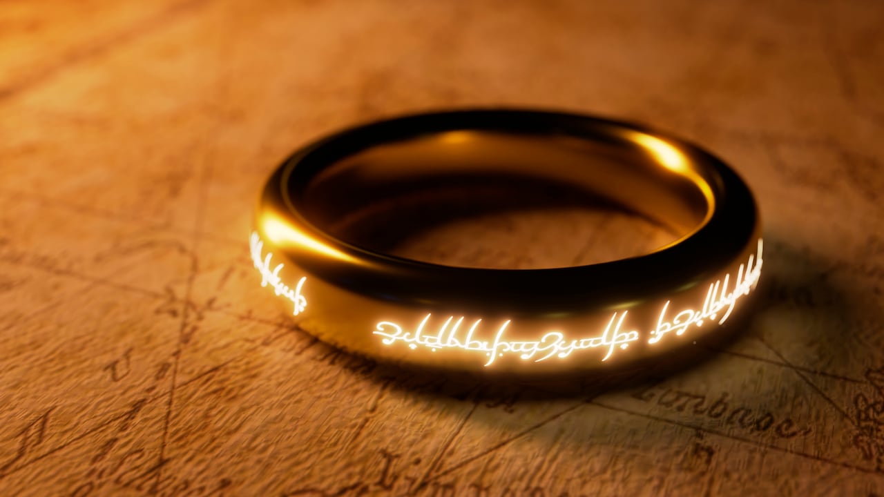 El idioma élfico fue creado por Tolkien para 'El señor de los anillos'. Inspirado por esa resonante obra, este anillo dorado con escritura élfica brillante reposa sobre un antiguo mapa de pergamino.