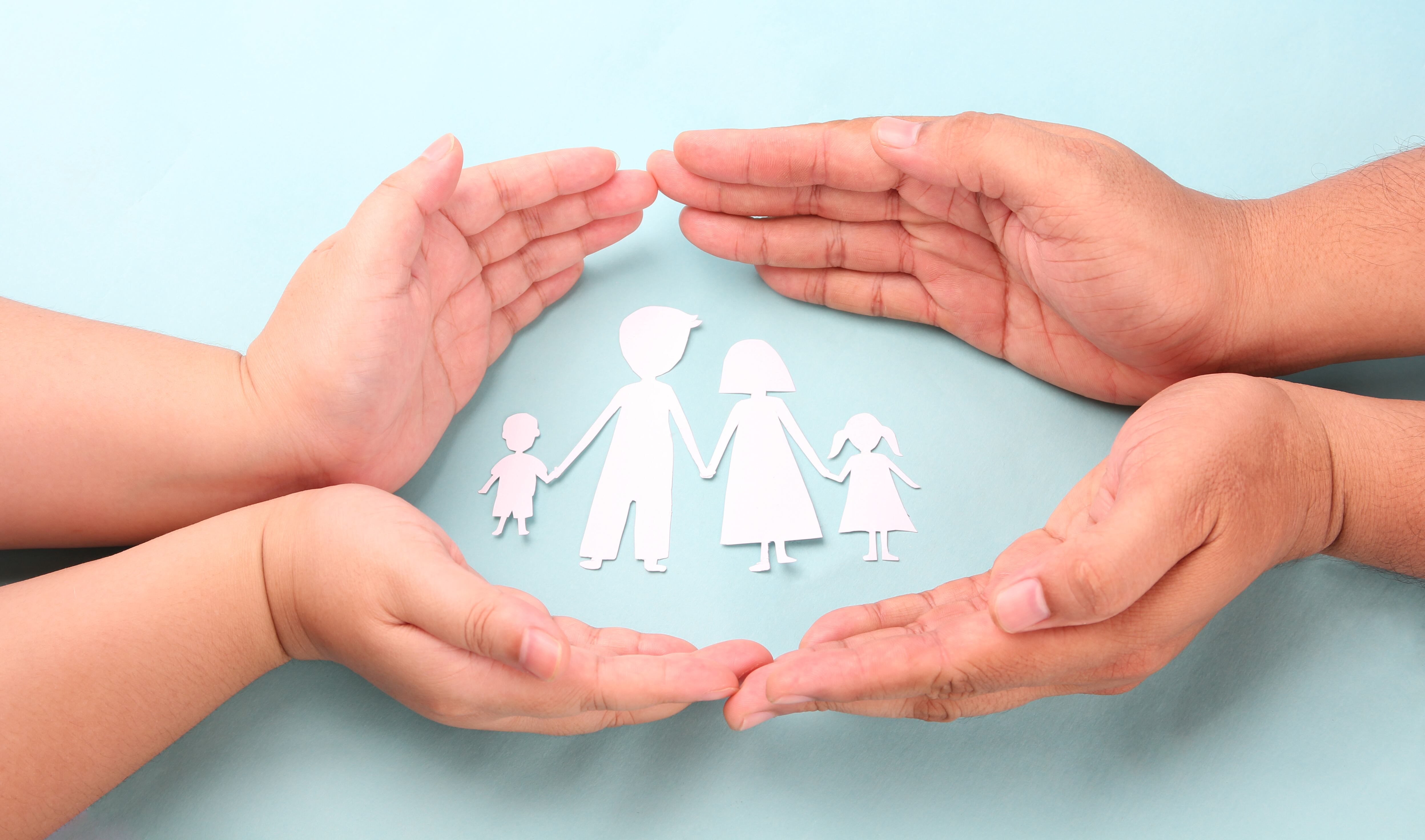 hands holding paper family cutout on blue background.