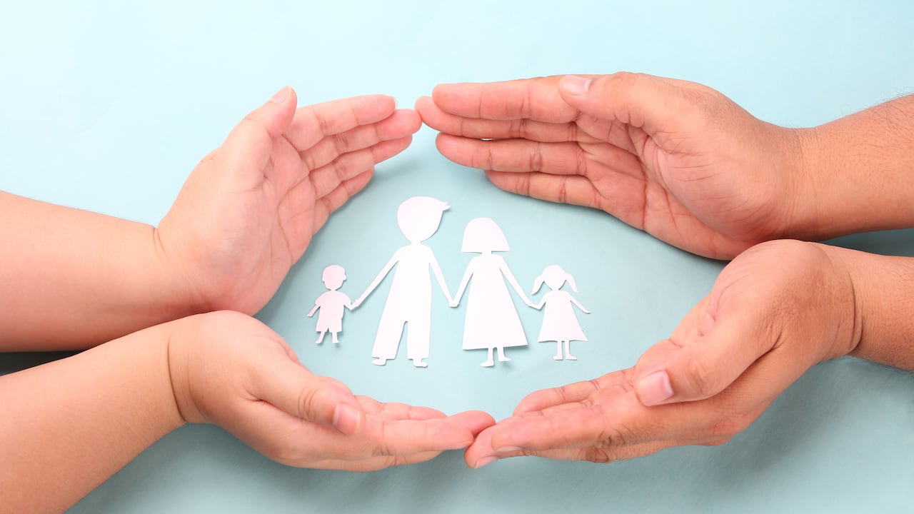 hands holding paper family cutout on blue background.