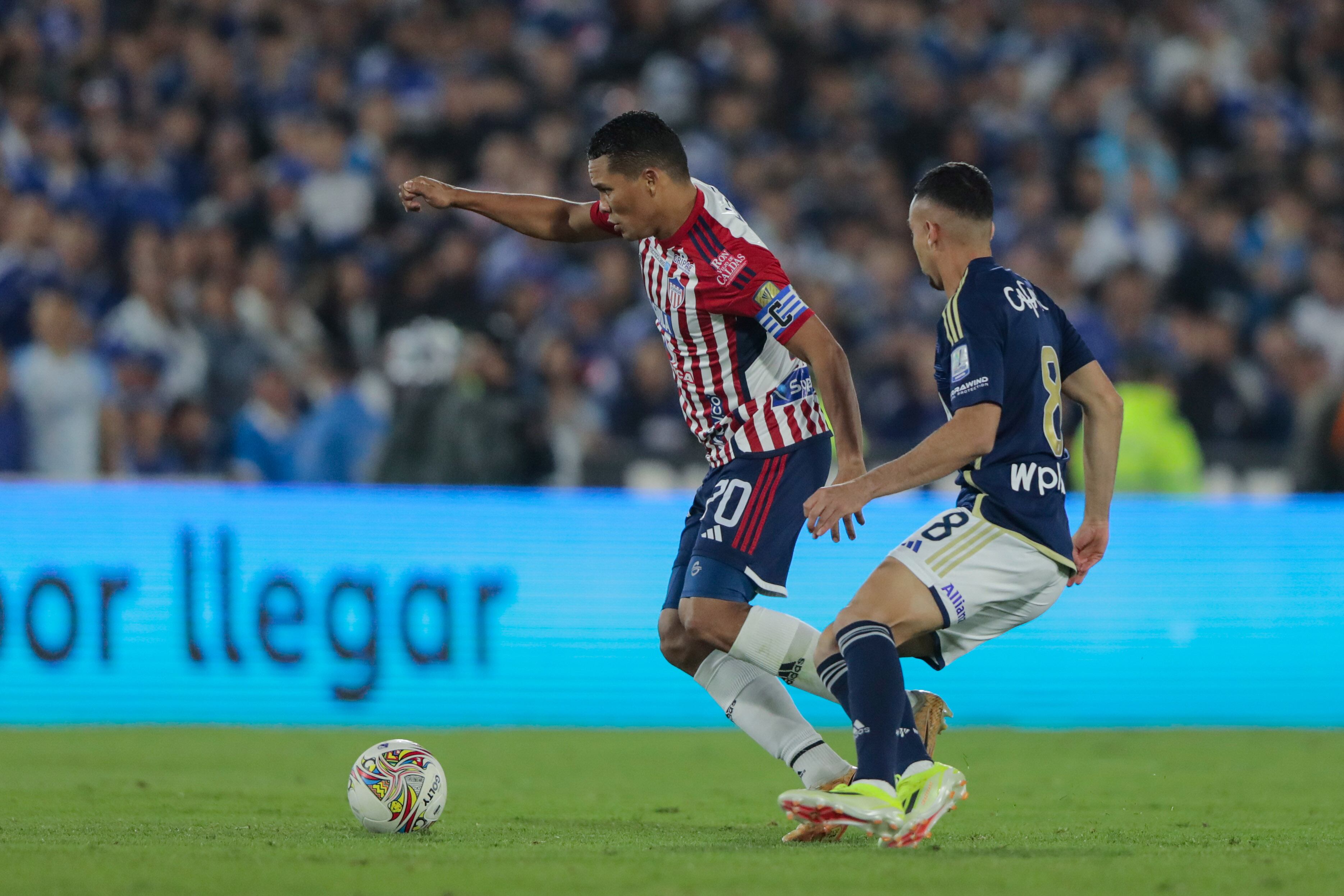 BOGOTA, COLOMBIA - APRIL 17: Carlos Bacca of Junior de Barranquilla competes for the ball with Daniel Giraldo of Millonarios F.C during a 17th round match between Millonarios F.C and Junior de Barranquilla as part of Primera A tournament at Estadio El Campin on April 17, 2024 in Bogota, Colombia. (Photo by Andres Rot/Getty Images)