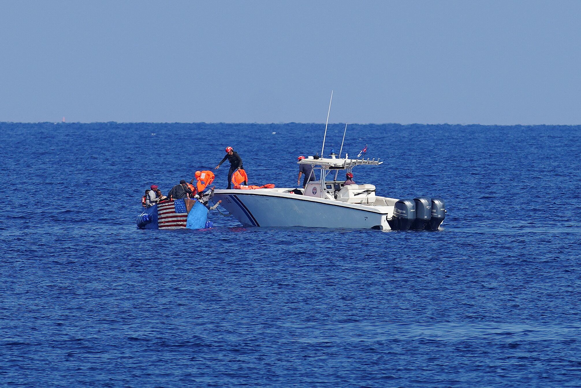 Guardacostas cubanos entregan chalecos salvavidas a hombres que intentaron emigrar ilegalmente a Estados Unidos antes de remolcar su bote cerca del Malecón frente al mar en La Habana, Cuba. REUTERS/Alexandre Meneghini