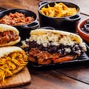 Desayuno latinoamericano, específicamente en países como Venezuela y Colombia, Arepas con varios ingredientes para rellenar como pollo, carne, frijoles negros, plátano frito. Todo sobre una mesa rústica de madera