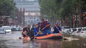 Los equipos de rescate recorren un vecindario donde fuertes lluvias han causado graves daños en la capital china.