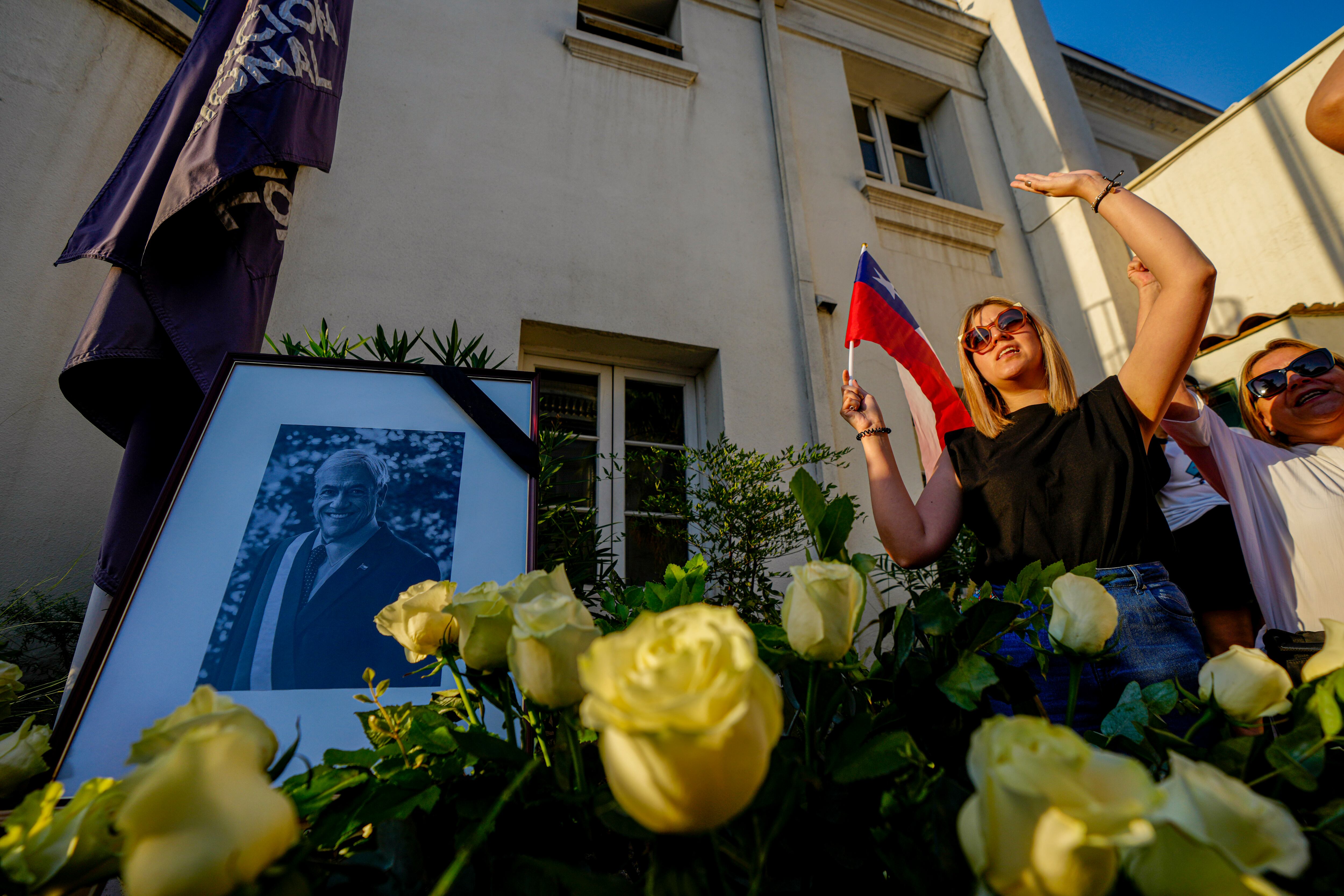 Simpatizantes cantan el himno nacional y gritan "larga vida a Piñera", junto al retrato del fallecido expresidente chileno Sebastián Piñera en el punto de homenaje colocado en la sede del partido Renovación Nacional, en Santiago, Chile, el martes 6 de febrero de 2024. El dos veces presidente chileno murió el martes en un accidente de helicóptero a los 74 años. (AP Foto/Esteban Félix)