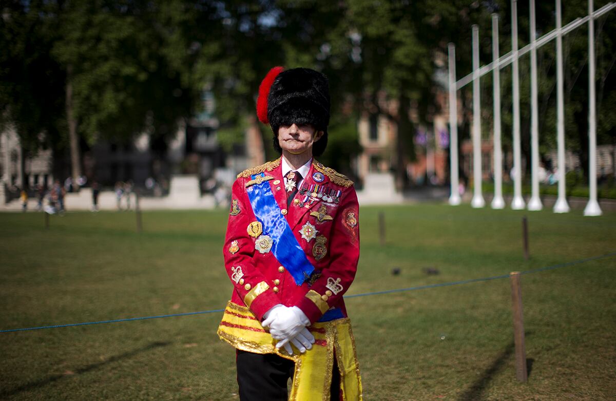 Un hombre en traje militar de ceremonia espera la carroza del desfile que escolta a la reina Isabel II hacia el Parlamento en Londres, en donde dará un discurso tras la victoria del Partido Conservador. (AP/Matt Dunham)