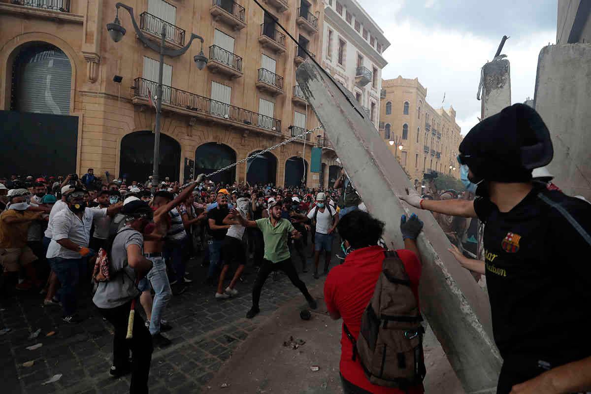 Los manifestantes retiran una losa de hormigón de una barrera para abrir la vía que conduce al edificio del parlamento. AP Photo / Hassan Ammar.