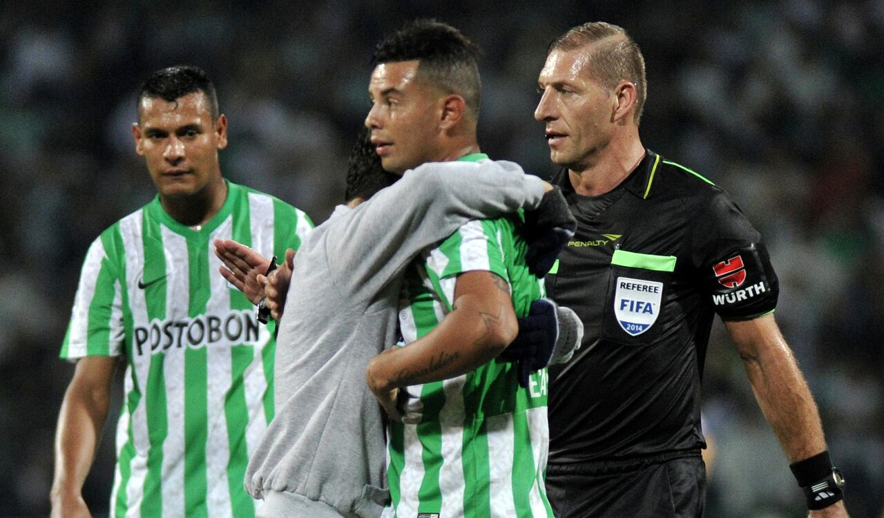 Edwin Cardona recibe el abrazo de un hincha en plena cancha mientras jugaba con Nacional.