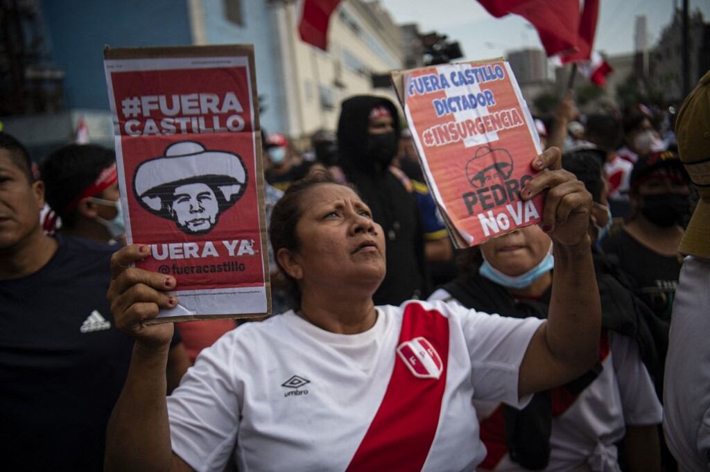 Una mujer sostiene carteles durante una protesta contra el gobierno del presidente de Perú, Pedro Castillo, en Lima el 05 de abril de 2022 - El presidente peruano, Pedro Castillo, anunció el fin del toque de queda en la capital, Lima, con el objetivo de contener las protestas contra el aumento de los precios del combustible tras las conversaciones de crisis con Congreso. (Foto por ERNESTO BENAVIDES / AFP)