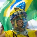 A woman wearing a face shield and mask decorated with an image of Brazilian President Jair Bolsonaro takes part in a demonstration to show support for Bolsonaro, after leaders of all three branches of the armed forces jointly resigned following the president's replacement of the defense minister, on Copacabana beach in Rio de Janeiro, Brazil, Wednesday, March 31, 2021. (AP Photo/Silvia Izquierdo)