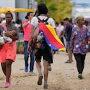 A migrant wears a Venezuelan flag in Necocli, Colombia, a stopping point for migrants taking boats to Acandi which leads to the Darien Gap, Thursday, Oct. 13, 2022. Some Venezuelans are reconsidering their journey to the U.S. after the U.S. government announced on Oct. 12 that Venezuelans who walk or swim across the border will be immediately returned to Mexico without rights to seek asylum. (AP Photo/Fernando Vergara)