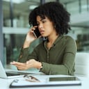 Shot of a young businesswoman looking stressed while using a laptop and smartphone in a modern office