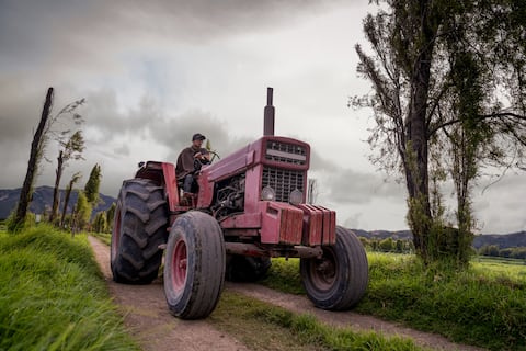 Agricultor latinoamericano conduciendo un camión tractor mientras trabajaba en una granja - conceptos de agricultura.
