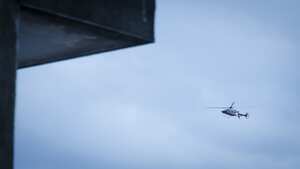 Helicopter flying over the city. The photo was taken on a cloudy afternoon from inside an old house using a telephoto lens.