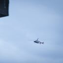 Helicopter flying over the city. The photo was taken on a cloudy afternoon from inside an old house using a telephoto lens.