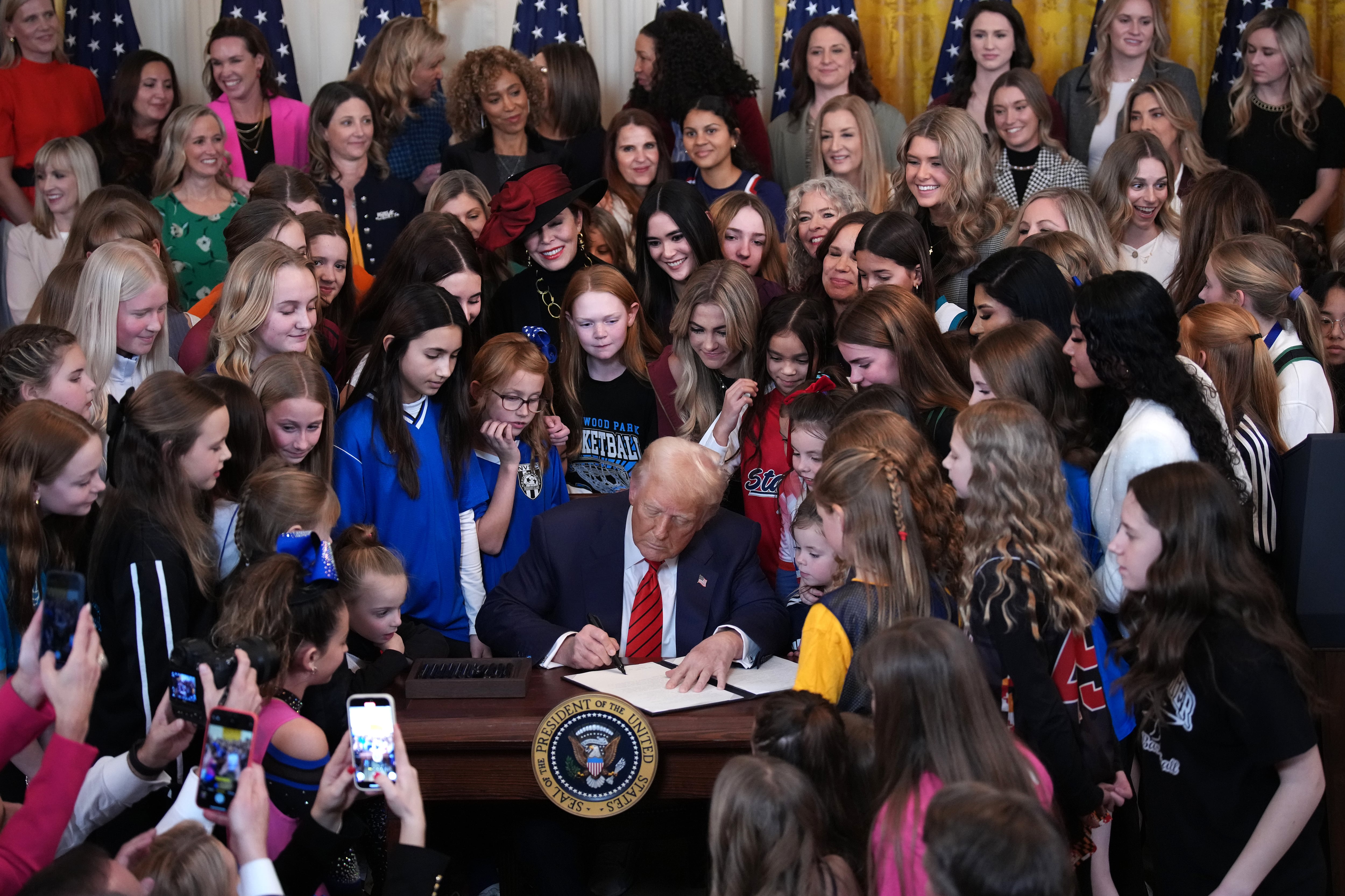 El presidente de los Estados Unidos, Donald Trump, acompañado por mujeres deportistas, firma la orden ejecutiva "No hombres en deportes femeninos" en el Salón Este de la Casa Blanca, el 5 de febrero de 2025