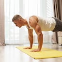 Hombre musculoso haciendo flexiones durante el entrenamiento en casa. Músculos, masa muscular, ejercicio físico, tonificar.