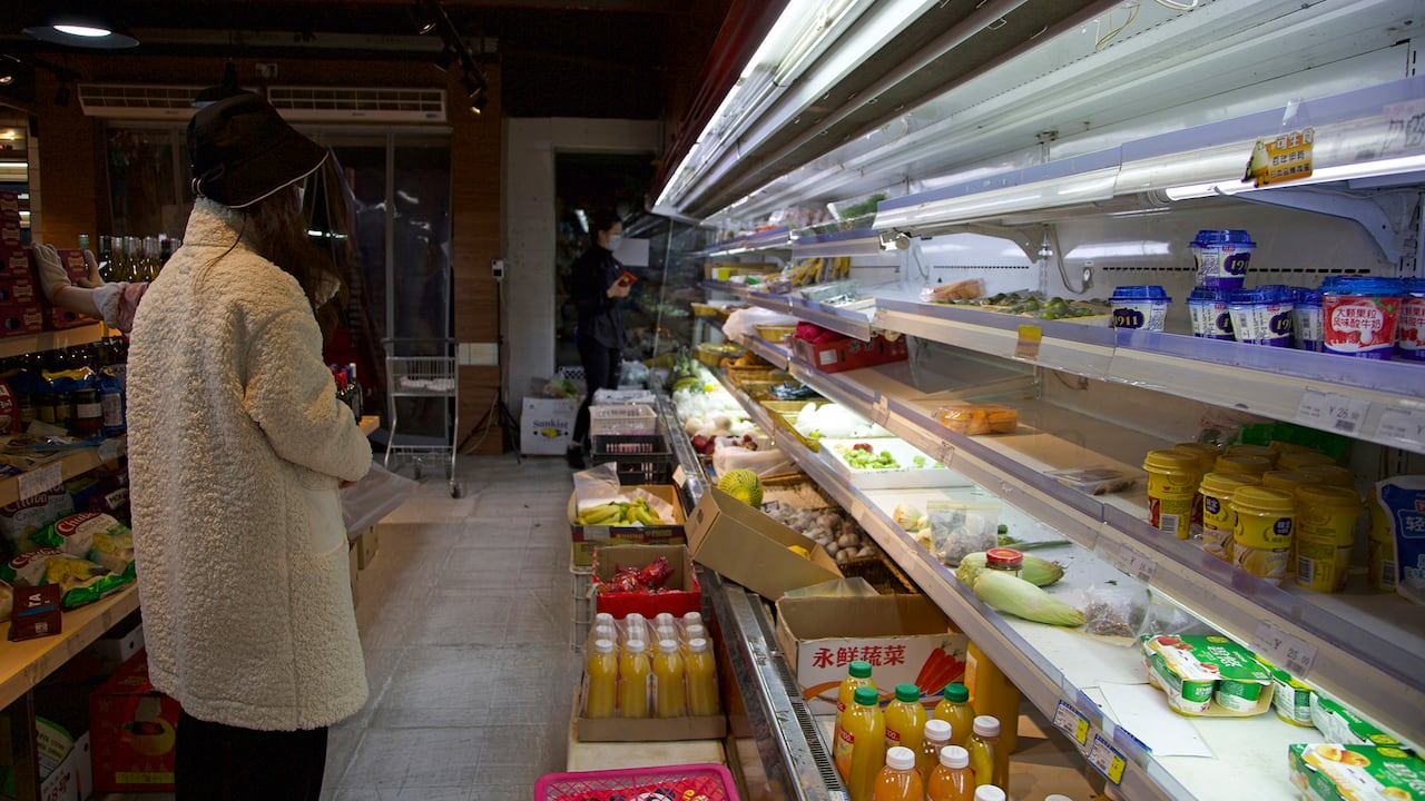 Un cliente se para cerca de los estantes parcialmente vacíos en un supermercado en Shanghái, China.