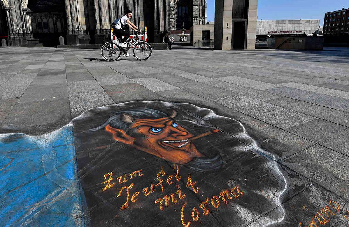 Esta imagen del 17 de marzo fue tomada en la ciudad alemana de Colonia. El grafiti en el suelo dice "al diablo con corona". La ciudad cerró todos los bares y restaurantes debido al brote de coronavirus. Todos los eventos públicos y privados están prohibidos. Foto: Martin Meissner/ AP. 