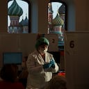 Una trabajadora médica prepara una dosis de la vacuna rusa contra el COVID-19 Sputnik Lite, en un centro de vacunación en una tienda GUM, en la Plaza Roja, con la catedral de San Basilio al fondo, en Moscú, Rusia, el 26 de octubre de 2021. (AP Foto/Pavel Golovkin)