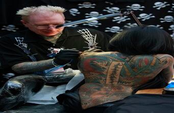 Visitantes exponen sus diseños mientras son tatuados.