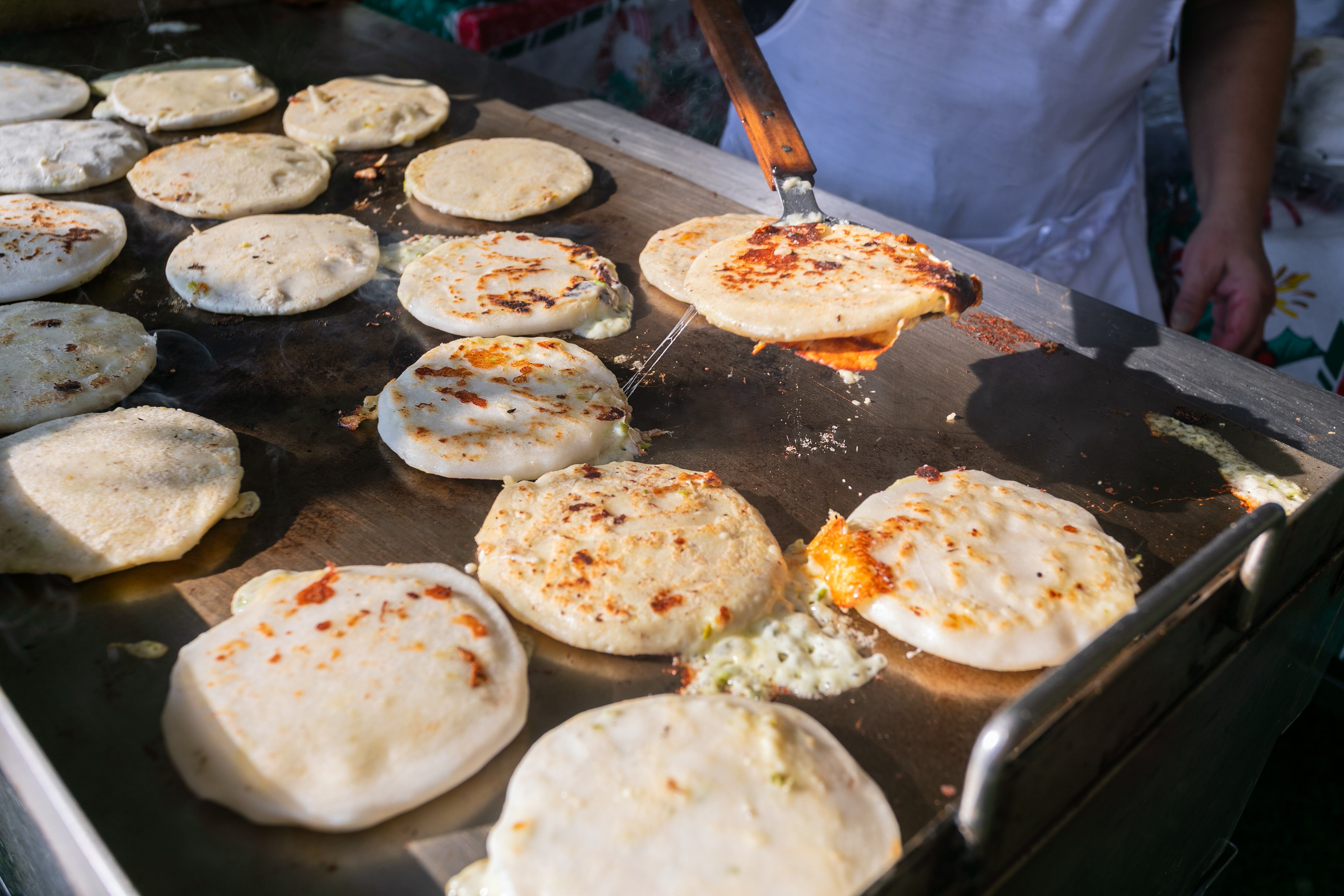 Pupusas siendo preparadas en un comal de gas caliente. Comida tradicional salvadoreña.