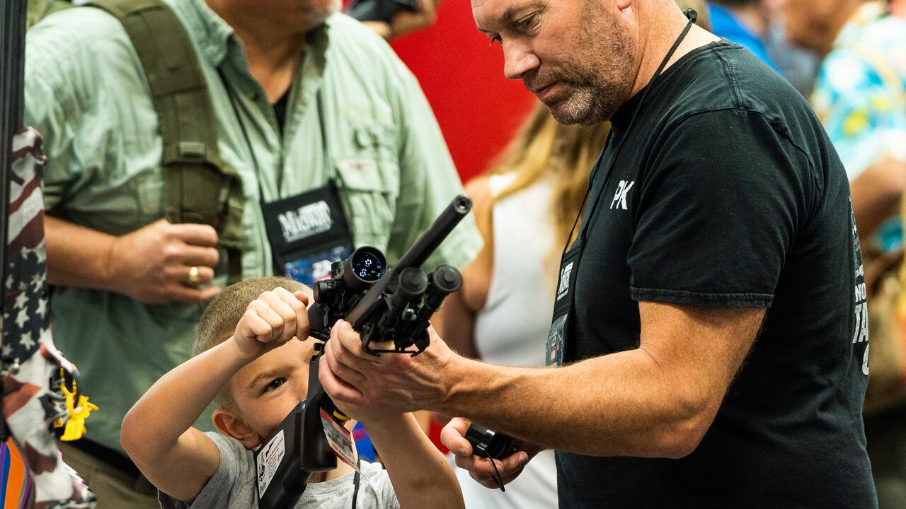Un asistente le muestra a un niño cómo sostener y cargar un arma durante la convención anual de la Asociación Nacional del Rifle (NRA) en el Centro de Convenciones de Indiana en Indianápolis, Indiana, el sábado 15 de abril de 2023.