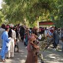Taliban fighters and local people are pictured along the street in Jalalabad province on August 15, 2021. (Photo by - / AFP)