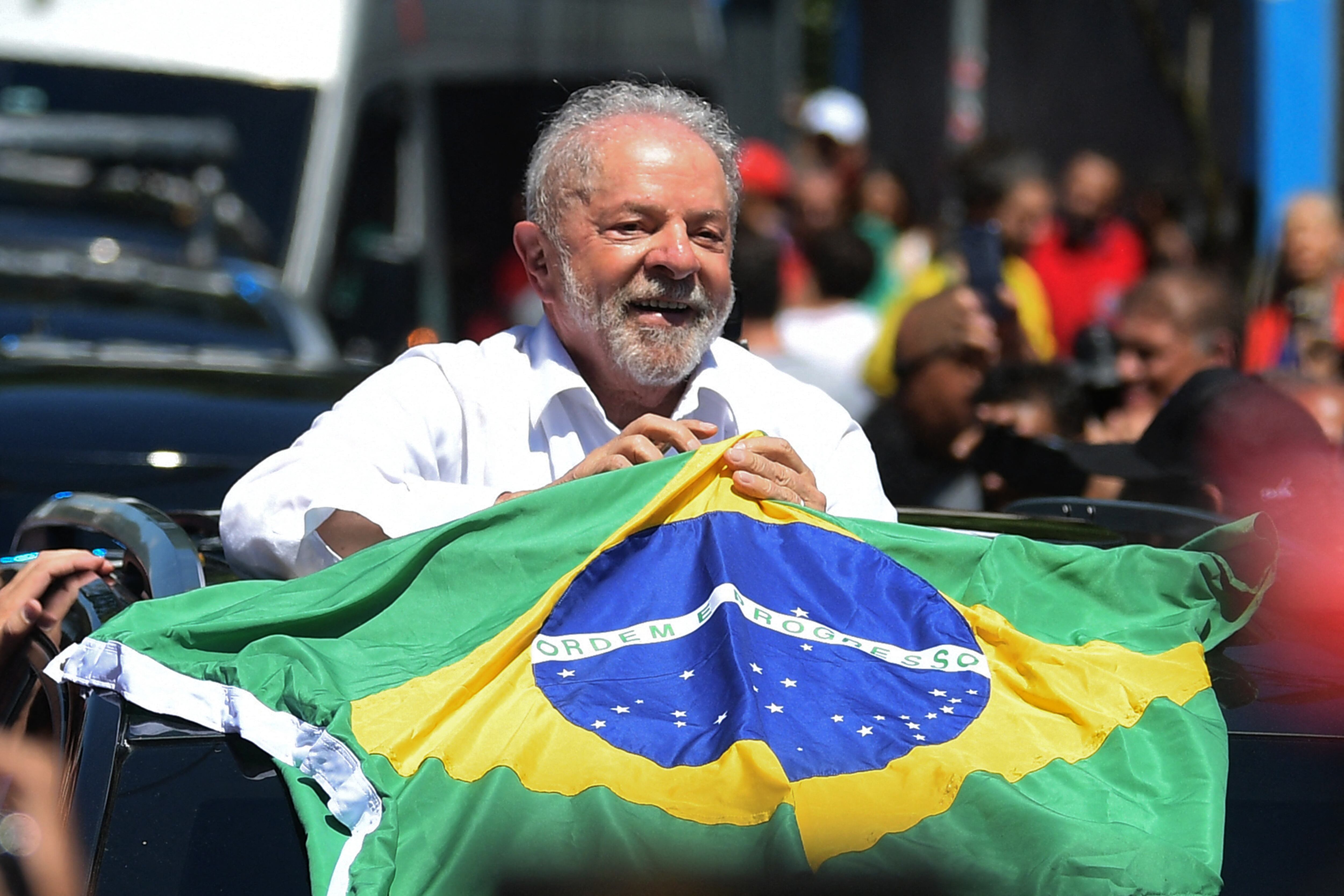 El expresidente brasileño (2003-2010) y candidato del izquierdista Partido de los Trabajadores (PT) Luiz Inácio Lula da Silva sostiene una bandera brasileña al salir de un colegio electoral durante la segunda vuelta de las elecciones presidenciales en Sao Paulo, Brasil, el 30 de octubre de 2019. 2022. - Después de una campaña amargamente divisiva y una primera ronda electoral inconclusa, Brasil elige a su próximo presidente en una segunda vuelta de suspenso entre el titular de extrema derecha Jair Bolsonaro y el veterano izquierdista Luiz Inacio Lula da Silva. (Foto de CARL DE SOUZA / AFP)